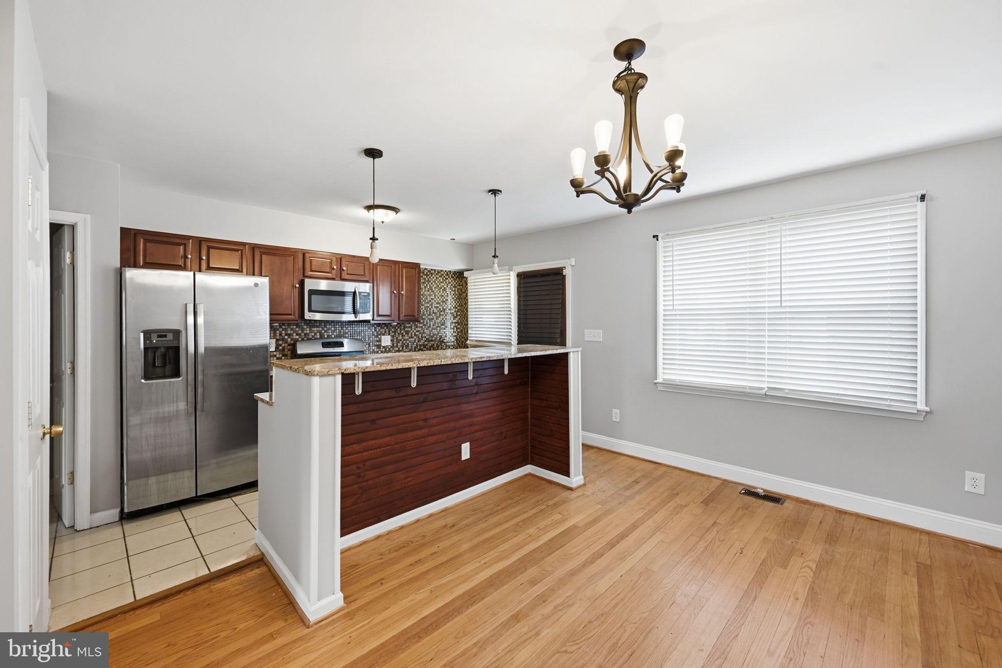 3723 Yolando Road Baltimore, MD 21218 - Photo 12 of 42 a kitchen with kitchen island granite countertop a refrigerator oven a sink and a wooden floor