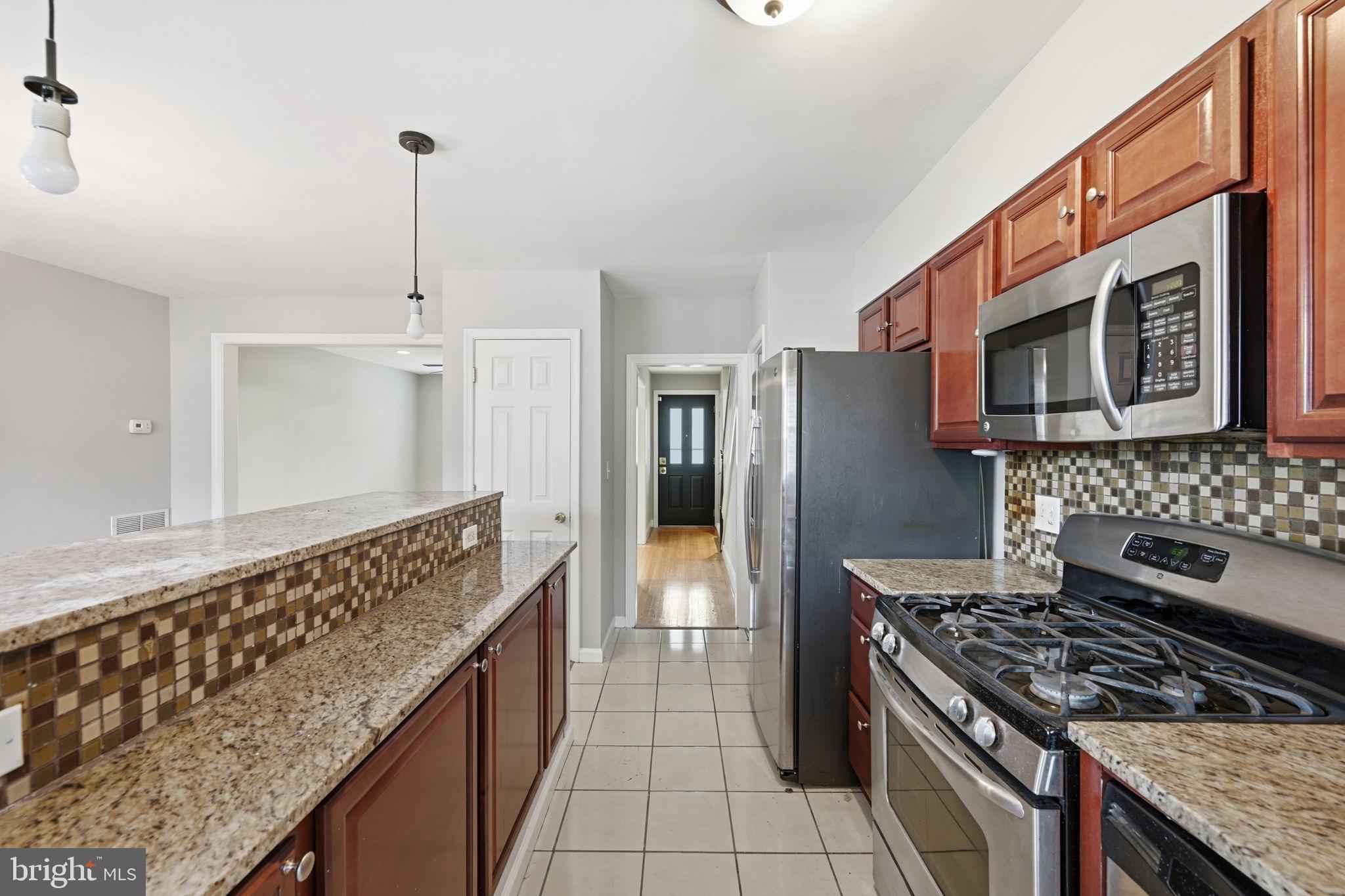 3723 Yolando Road Baltimore, MD 21218 - Photo 16 of 42 a kitchen with stainless steel appliances granite countertop a stove a refrigerator and a wooden cabinets