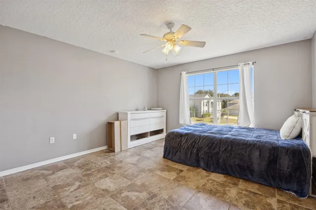 a view of an empty room with window and chandelier fan
