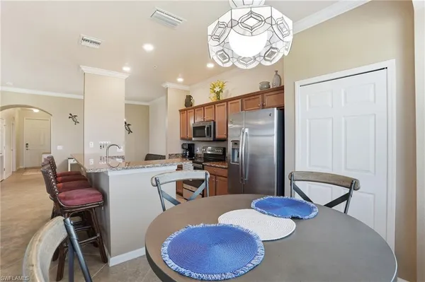a kitchen with stainless steel appliances kitchen island granite countertop a table chairs in it and wooden floors