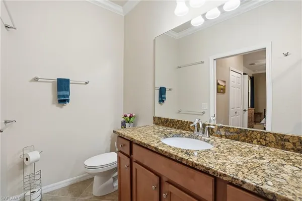 a bathroom with a granite countertop sink a toilet and a mirror