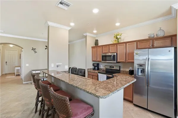 a kitchen with granite countertop a table chairs microwave and refrigerator