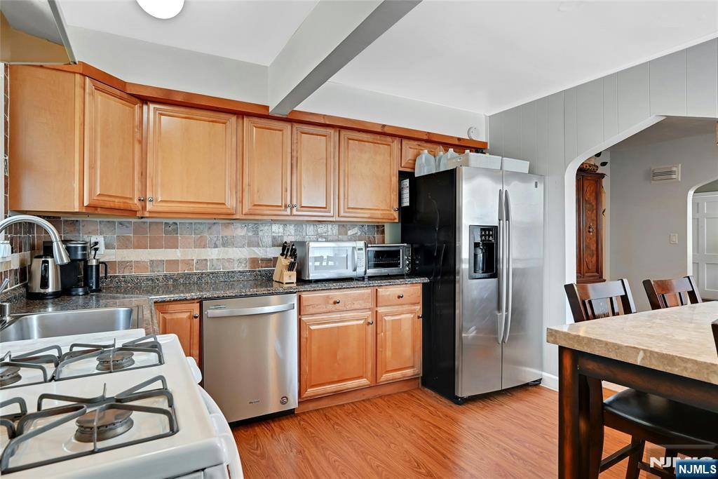 85 Edison Street Clifton, NJ 07013 - Photo 9 of 28 a kitchen with stainless steel appliances granite countertop a refrigerator a sink dishwasher a stove and white countertops with wooden floor