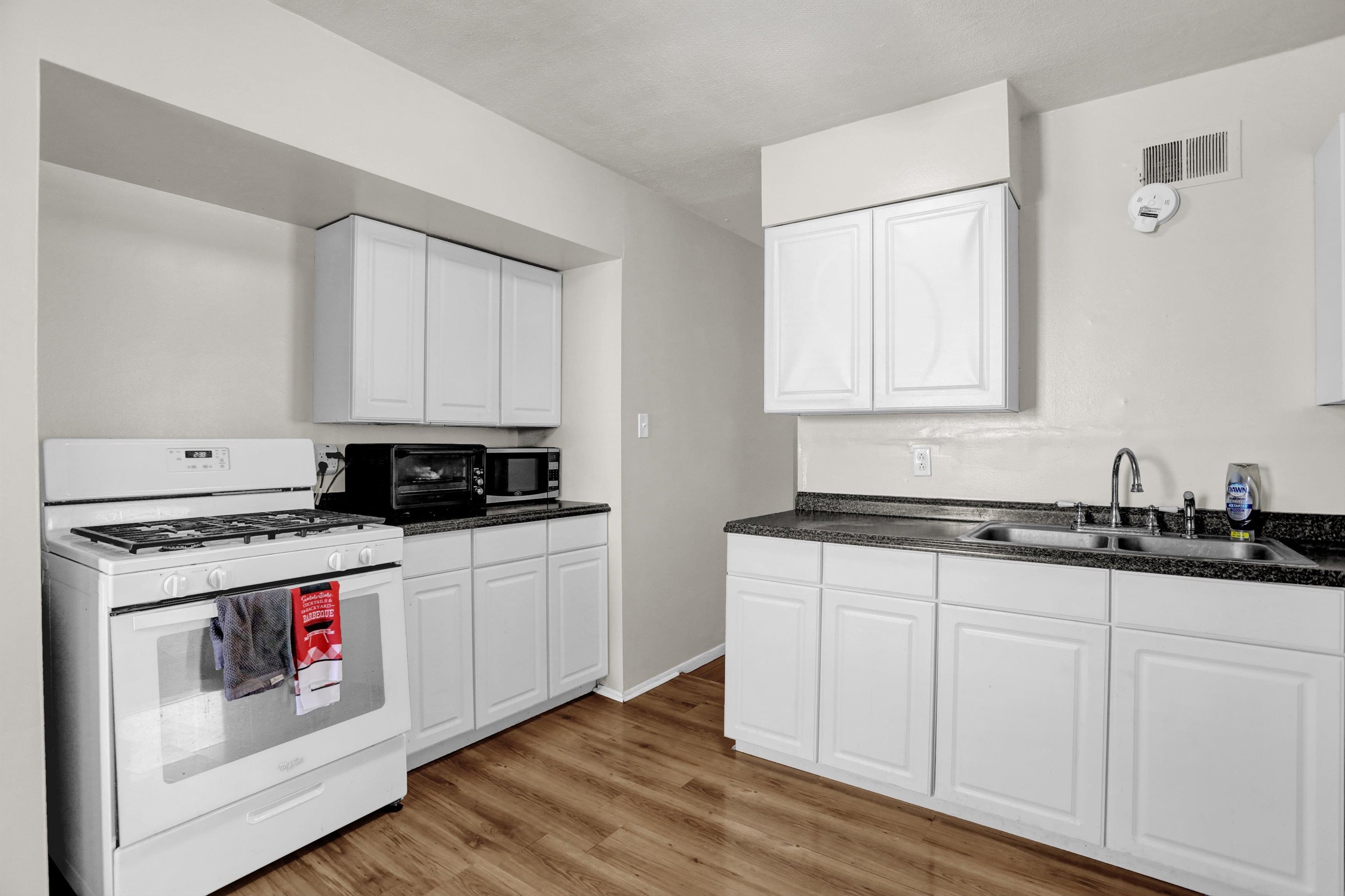 4931 Owen Road Memphis, TN 38122 - Photo 11 of 24 Kitchen featuring visible vents, dark countertops, white gas range, white cabinetry, and a sink