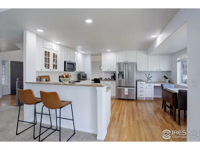 a kitchen with stainless steel appliances a refrigerator a stove a sink dishwasher and a dining table with wooden floor