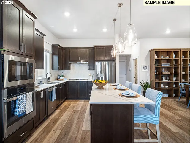 a kitchen with stainless steel appliances kitchen island granite countertop a stove a sink a refrigerator and chairs