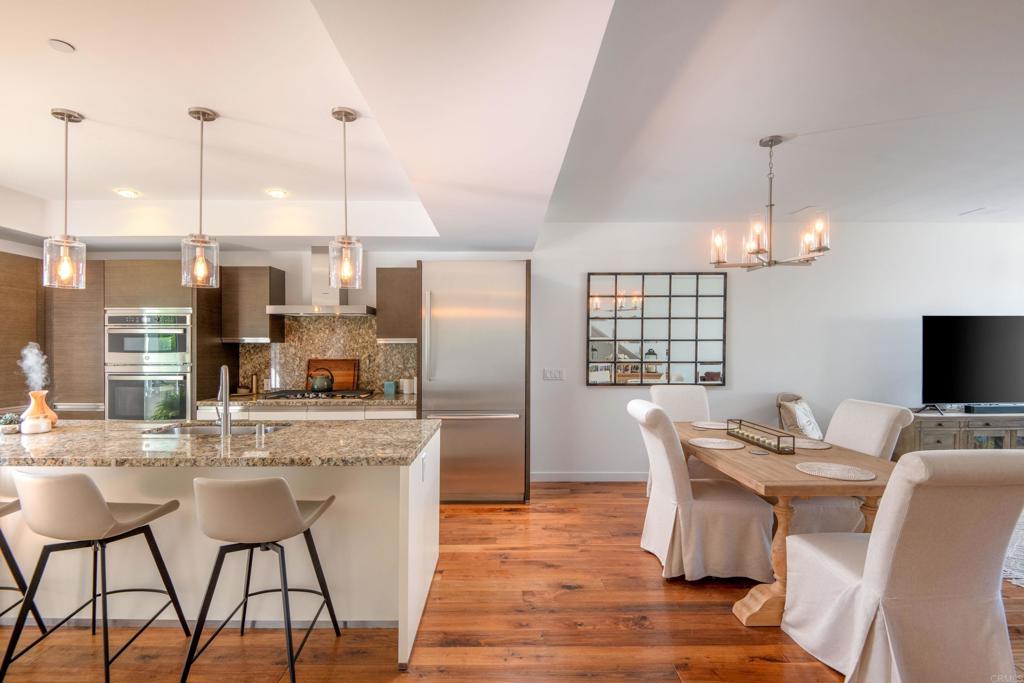 90 North Coast Highway 101, Unit 310 Encinitas, CA 92024 - Photo 7 of 24 a kitchen with stainless steel appliances kitchen island granite countertop a dining table chairs and a refrigerator