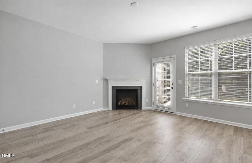 6626 Clarksburg Place Raleigh, NC 27616 - Photo 9 of 25 an empty room with wooden floor fireplace and windows