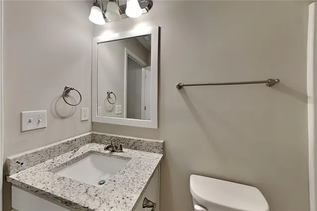 a bathroom with a granite countertop sink a toilet and a mirror