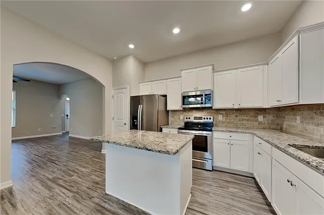 a large kitchen with stainless steel appliances granite countertop a stove and a sink