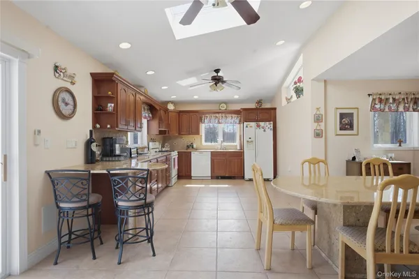 a kitchen with stainless steel appliances kitchen island granite countertop a dining table chairs and a refrigerator