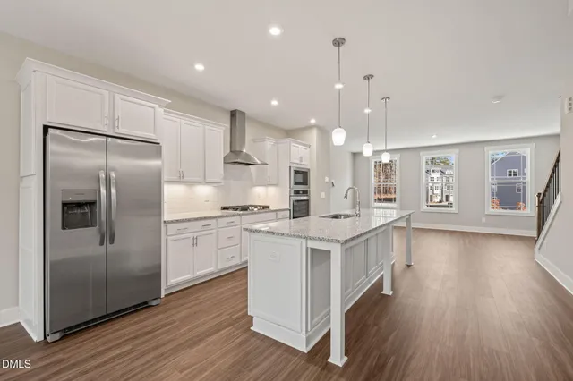 a kitchen with stainless steel appliances granite countertop a refrigerator a sink dishwasher a stove and white countertops with wooden floor