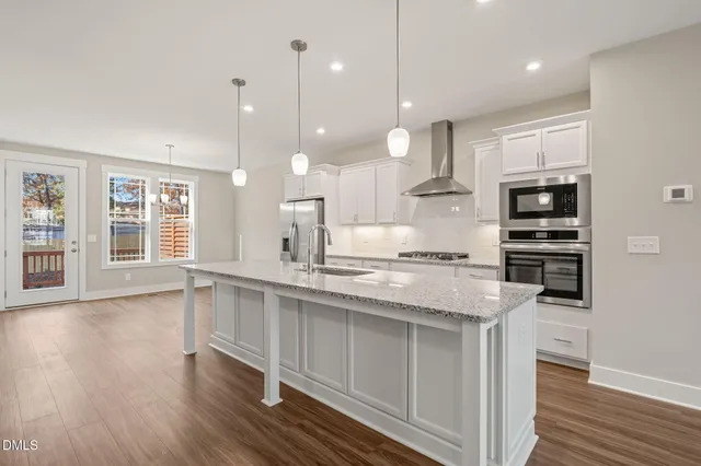 a large kitchen with kitchen island a stove a sink a refrigerator and a wooden floor