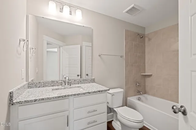 a bathroom with a granite countertop toilet a sink and a bathtub