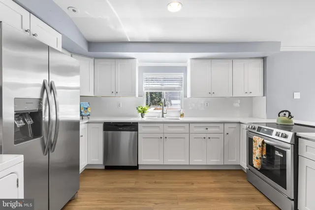 a kitchen with stainless steel appliances white cabinets and wooden floors