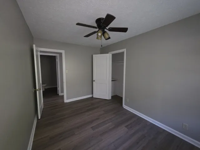 a view of a hallway with wooden floor and a ceiling fan