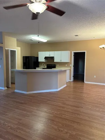 a view of an empty room with a kitchen and a window