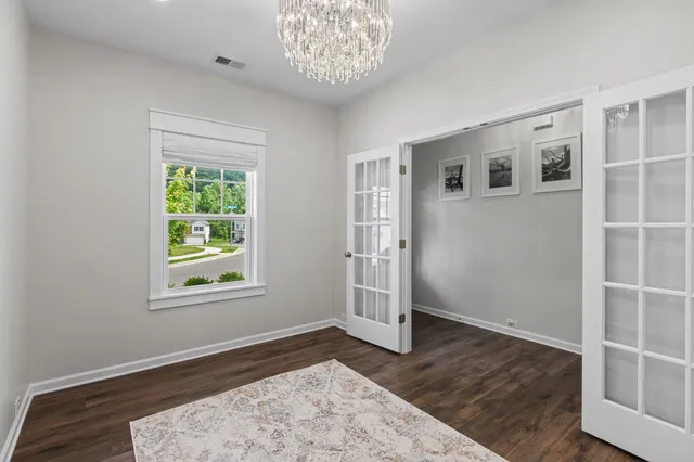 an empty room with wooden floor cabinet and windows