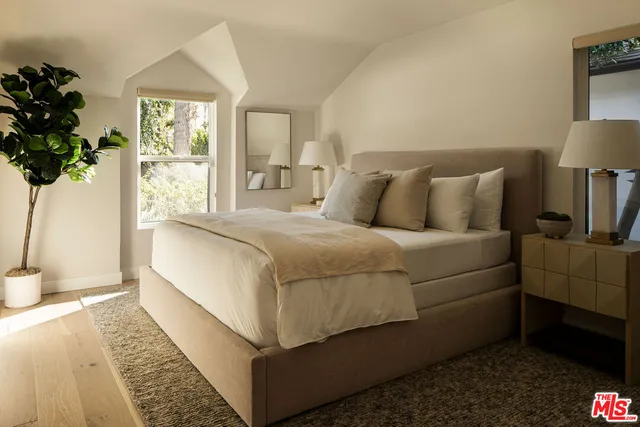 a bedroom with a large bed and a potted plant