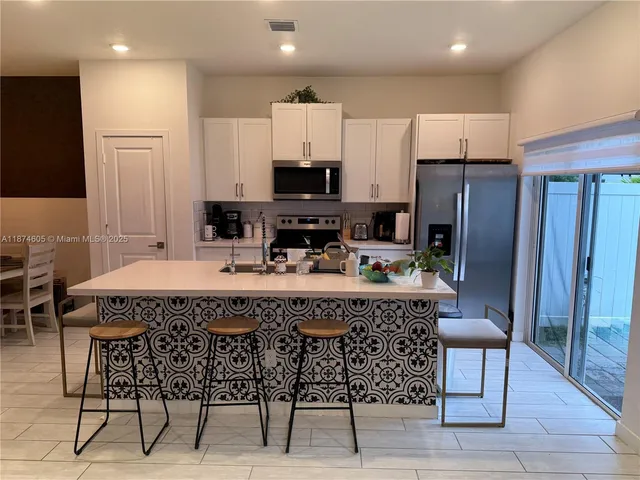 a kitchen with stainless steel appliances granite countertop a table chairs sink refrigerator and microwave