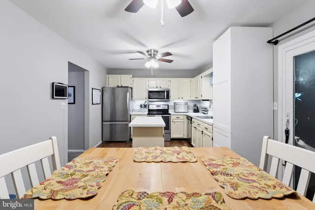 a kitchen with stainless steel appliances kitchen island granite countertop a sink dishwasher a refrigerator with a dining table and chairs