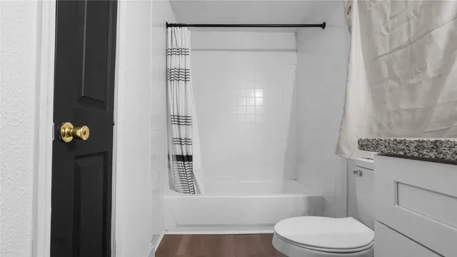 a bathroom with a granite countertop bathtub shower sink vanity and toilet