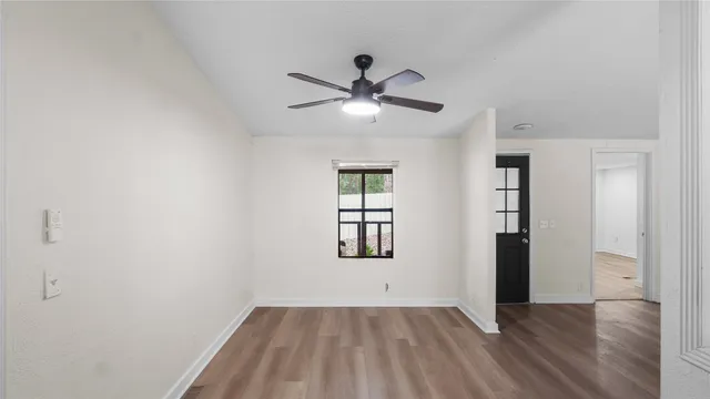 an empty room with wooden floor ceiling fan and windows