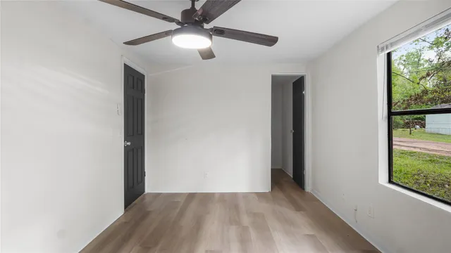 an empty room with windows and ceiling fan