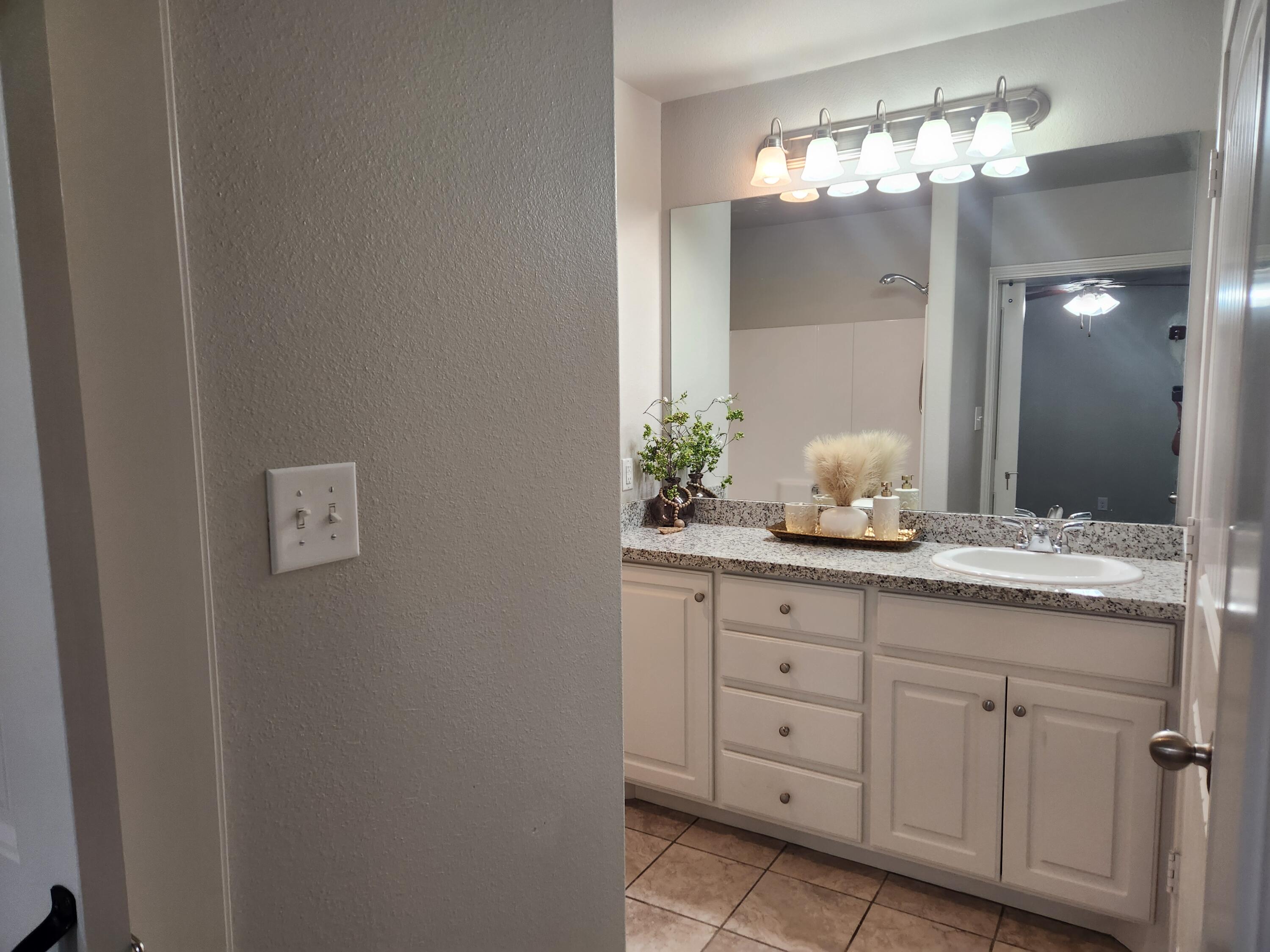 8702 13th Street Lubbock, TX 79416 - Photo 9 of 25 a bathroom with a granite countertop sink and a mirror
