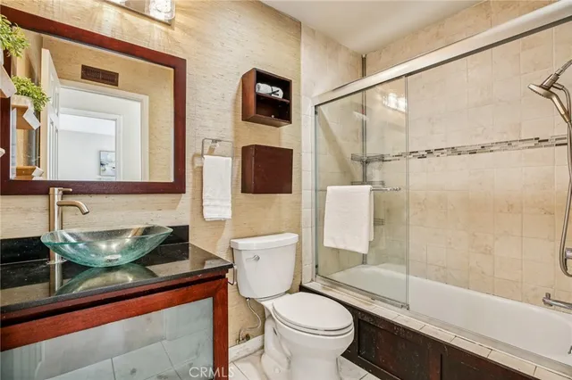 a bathroom with a granite countertop sink a toilet a mirror and shower