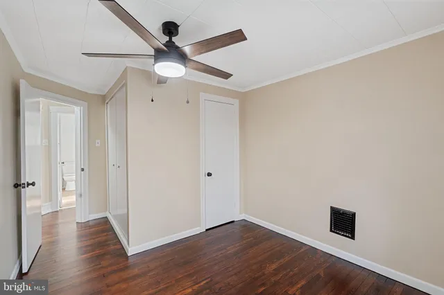 an empty room with wooden floor ceiling fan and window