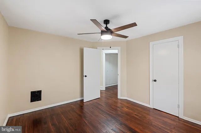 an empty room with wooden floor and a ceiling fan