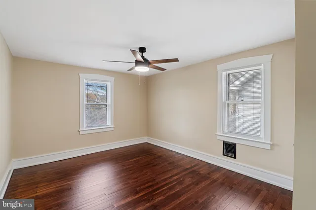 a view of empty room with wooden floor and fan