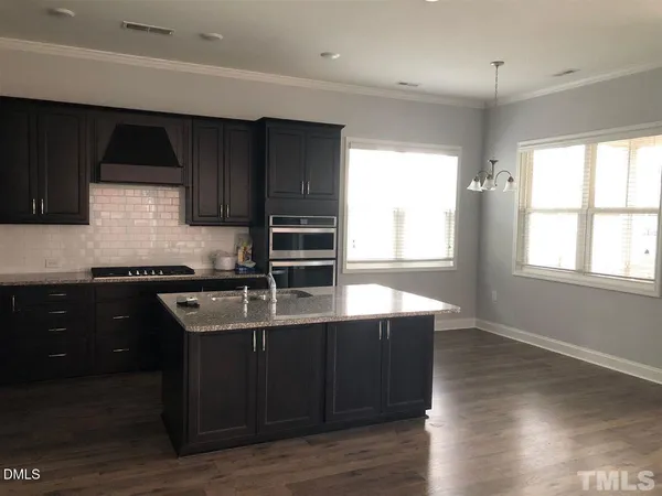 a kitchen with kitchen island granite countertop a sink cabinets and wooden floor