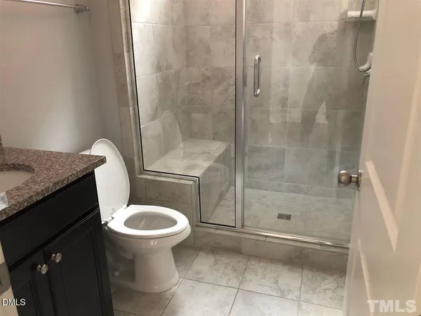 a bathroom with a granite countertop toilet a sink and a shower