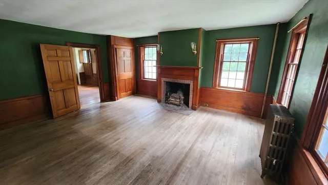 an empty room with wooden floor and fireplace