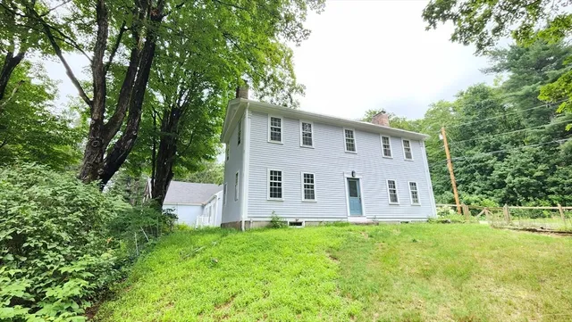 a view of a house with backyard and trees