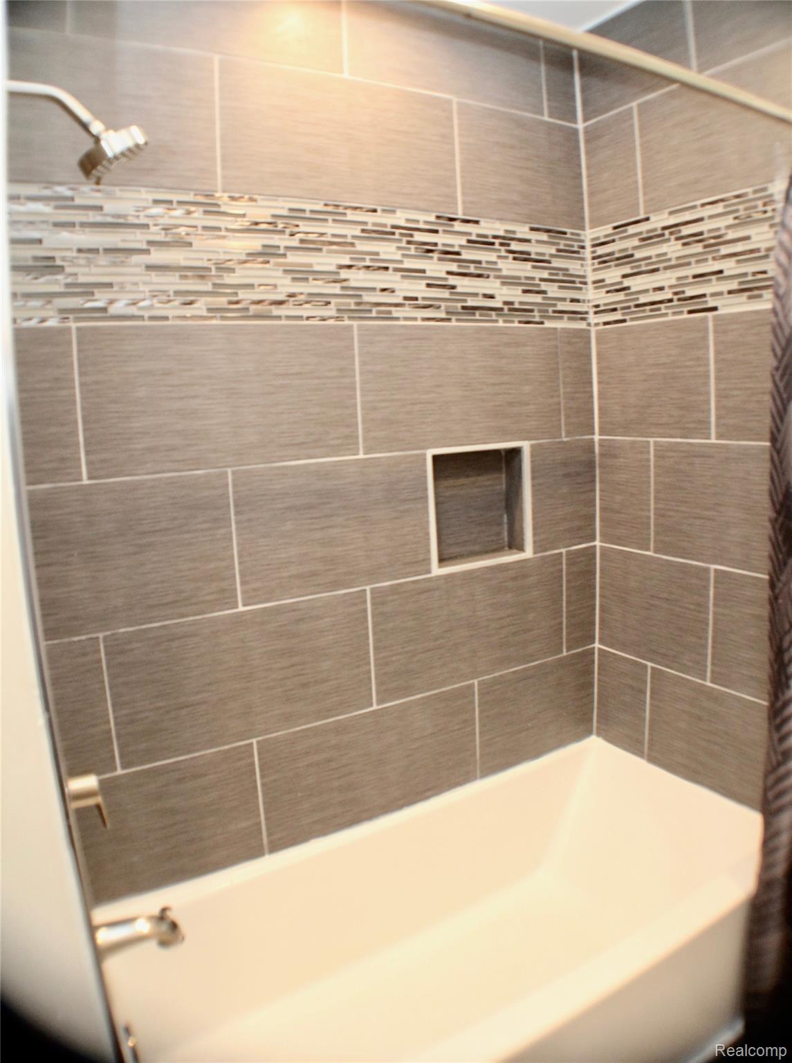 3231 West Utica Road Utica, MI 48317 - Photo 12 of 20 Bathtub with a tiled shower surround, mosaic accent tile, and a recessed niche