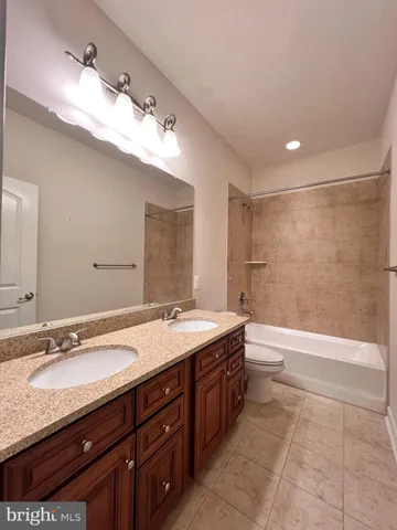 a spacious bathroom with a granite countertop sink a toilet a mirror and bathtub