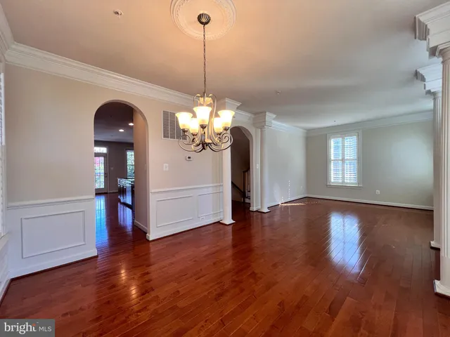 a view of a room with wooden floor chandelier and windows