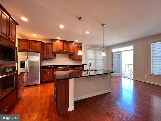 a kitchen with stainless steel appliances granite countertop a sink a stove and a wooden floor