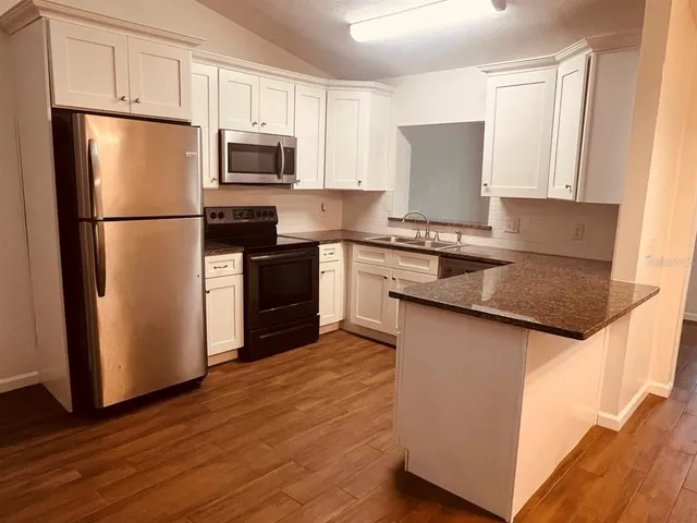 a kitchen with granite countertop a refrigerator stove and microwave