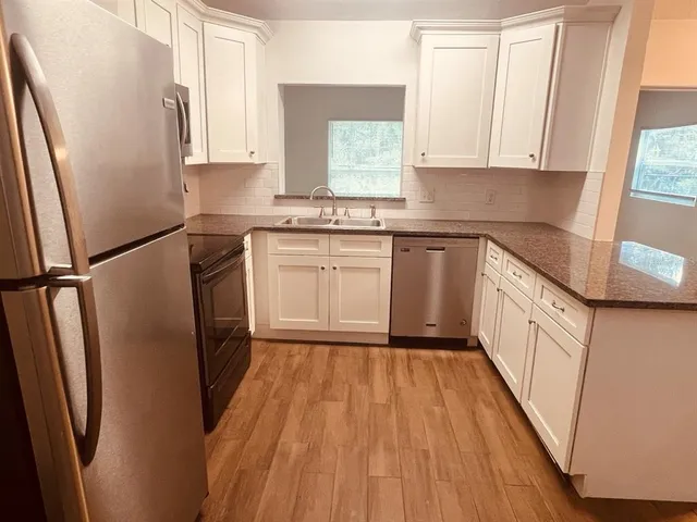 a kitchen with stainless steel appliances a refrigerator sink and wooden floor