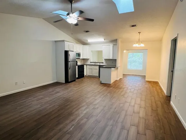 a view of a kitchen with wooden floor and a refrigerator