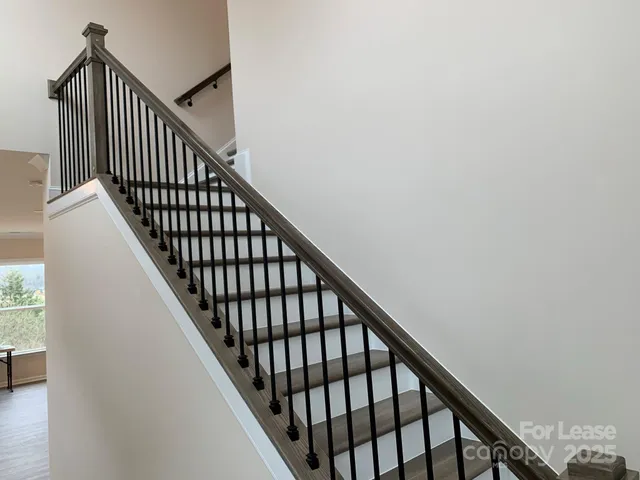 a view of staircase with wooden floor and white walls