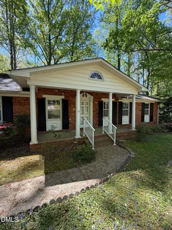 a front view of a house with a yard and potted plants