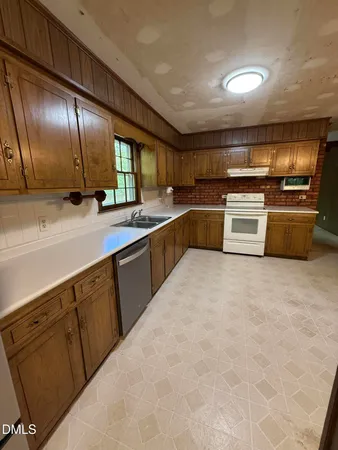 a large kitchen with stainless steel appliances wooden cabinets and a sink