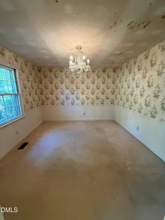 an empty room with a fireplace and chandelier