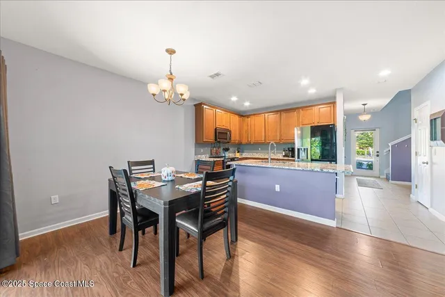 a kitchen with stainless steel appliances granite countertop a kitchen island hardwood floor and a view of living room