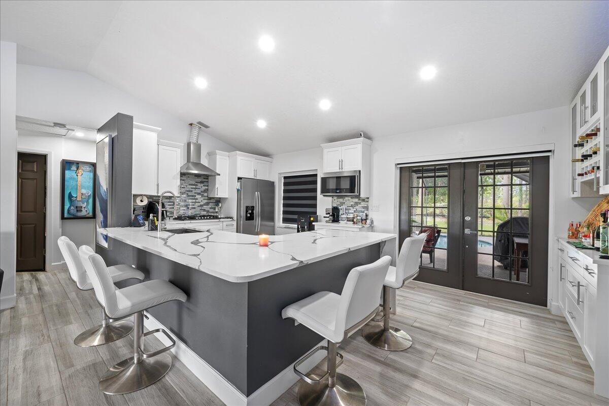 613 Grant Road Palm Bay, FL 32909 - Photo 8 of 40 a kitchen with stainless steel appliances kitchen island granite countertop a table chairs cabinets and wooden floor